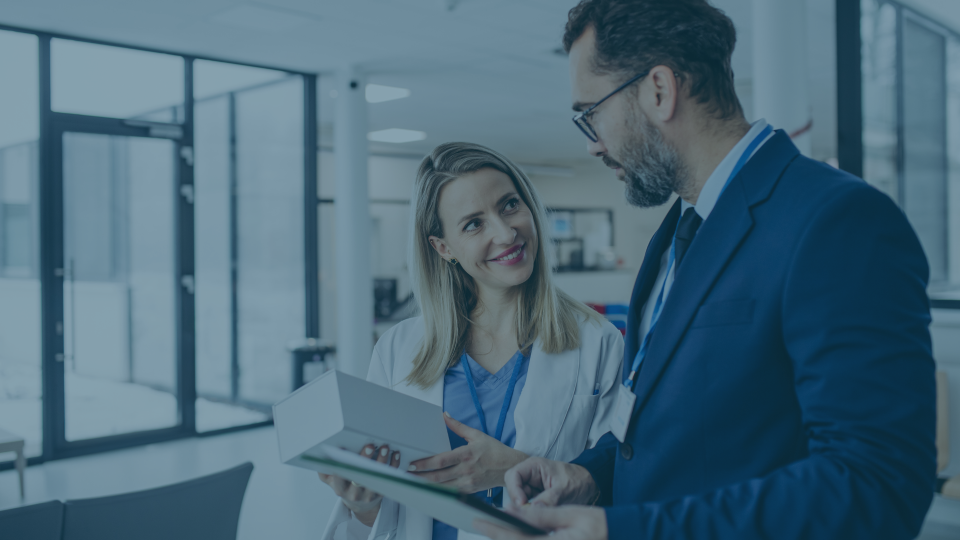 Medical device executive and clinical team leader reviewing product packaging and compliance documentation in a healthcare facility